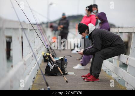 (210921) -- AUCKLAND, Sept. 21, 2021 (Xinhua) -- People go fishing at a wharf near Mission Bay of Auckland, New Zealand on Sept. 19, 2021. New Zealand's largest city Auckland will relax restrictions by moving to COVID-19 Alert Level 3 at 11:59 p.m. on Tuesday for at least two weeks, as the country reported 22 new Delta community cases on Monday. The city has remained at level 4, the top-level COVID-19 lockdown, for more than 30 days, longer than last year's lockdown, with schools and none-essential businesses closed. The rest of the country will stay at Alert Level 2, which means busine Stock Photo