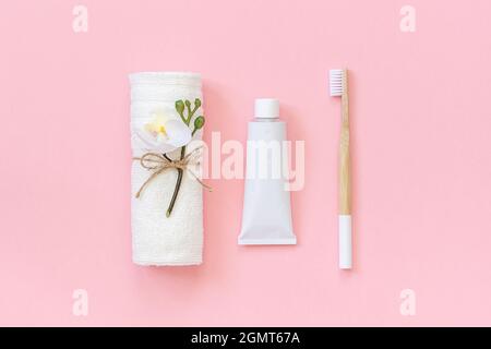 Natural eco-friendly bamboo brush, white towel and tube of toothpaste. Set for washing and brushing your teeth on pink background. Template for design Stock Photo