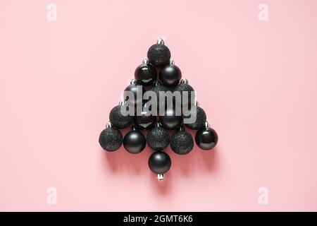 Abstract Christmas tree made of black bauble balls decoration on pink background. Minimal style Creative flat lay Top view Concept Merry christmas or Stock Photo