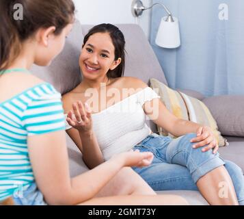 Cheerful teens girls blabbing on sofa Stock Photo