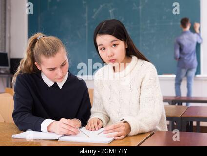 Tired female students during writing notes in classroom Stock Photo