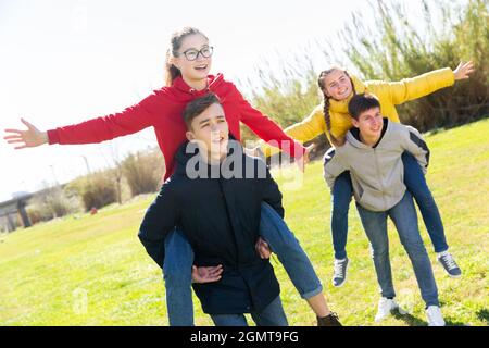 Happy teenage boys piggybacking girls Stock Photo
