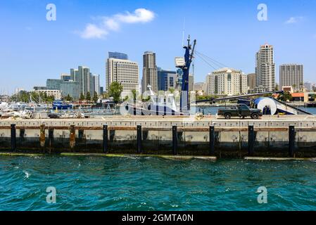 San Diego Harbor scene with pier and docked fishing boats and trawlers and cityscape of modern high rise buildings in downtown San Diego, CA Stock Photo