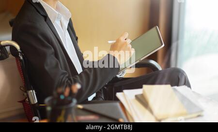 Cropped image of disabled businessman working on digital tablet with stylus pen on wheelchair Stock Photo