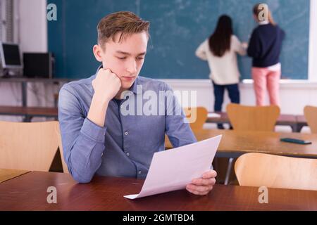 Young thoughtful guy preparing for the exam in classroom Stock Photo
