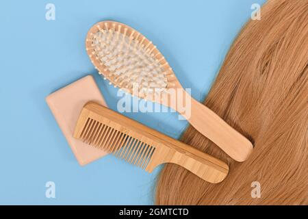 Healthy hair care routine with eco friendly solid shampoo bar, wooden comb and brush on blue background Stock Photo