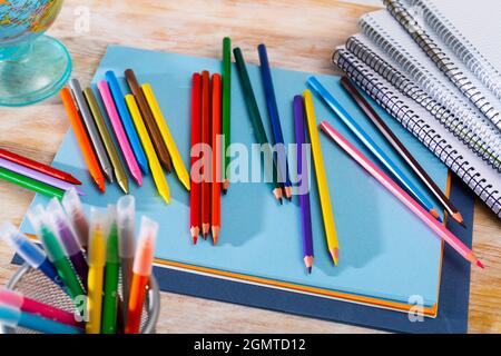 Colored pencils and sketchpads on wooden surface Stock Photo