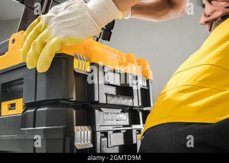 Worker and His Durable Plastic Made Tools Box Close Up Photo. Industrial Photo. Stock Photo