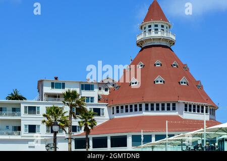 Close up of the unique red turret of the iconic 1888 Queen Anne Victorian style Hotel del Coronado in San Diego, CA against blue sky with people on th Stock Photo