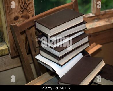stack of old books on a wooden chair, indoor close up Stock Photo