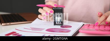 Women hands put stamp on documents and count on calculator Stock Photo