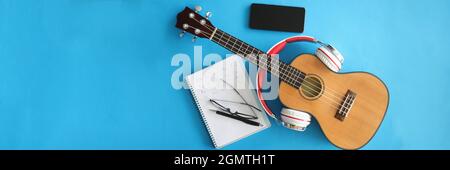 Guitar with headphones smartphones and notebook on blue background Stock Photo