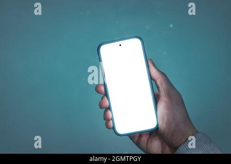 Hand holding a glowing smartphone with a blank screen Stock Photo