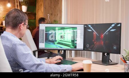 Game creator developing 3d videogame working at graphic ilustration in creative company office. Artist developer analyzing video game production using gaming software. Virtual environment on screen Stock Photo