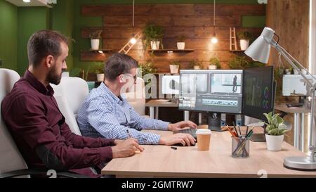 Team of video editors analyzing film montage after editing visual effects working in creative company office. Coworkers discussing movie production editing digital footage. Multimedia agency Stock Photo