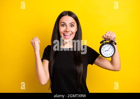 Portrait of astonished person fist up open mouth celebrate hold classic clock isolated on yellow color background Stock Photo