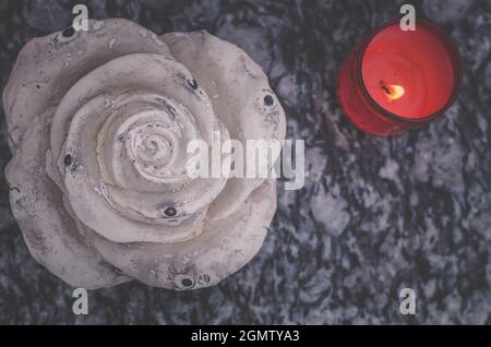 burning candle and white stone rose symbol Stock Photo