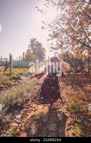 child in beautiful dress dancing wild in sunny afternoon Stock Photo