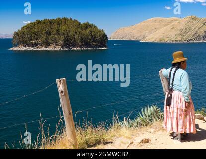 Lake Titicaca, Peru - 18 May 2018; one woman in shot   A tribal woman looks out over Lake Titicaca from the beautiful Island of the Sun. According to Stock Photo