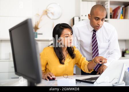 Focused male and female business colleagues looking at laptop screen, discussing new project in office Stock Photo