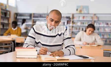Adult male student working in library, concept of adult education Stock Photo