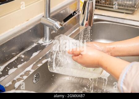 Close up hands of woman washing dishes in kitchen Stock Photo