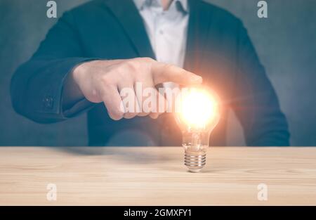 Business man point light bulbs, ideas, innovative technology and creativity. Idea innovation and inspiration concept.Hand man holding illuminated bulb Stock Photo