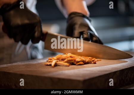 Cooking juicy beef steak by chef hands on dark black background with copy space for text menu or recipe. Stock Photo