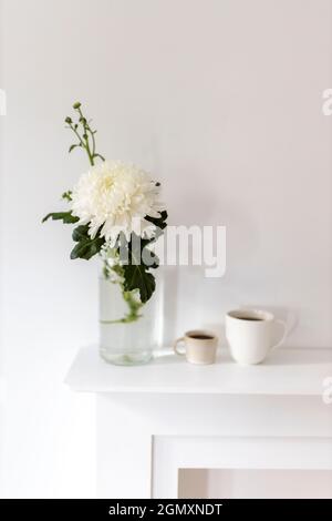 A large chrysanthemum in a glass vase, two fluted cups of coffee are on the table. Office decoration. Stock Photo