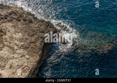 Aerial view of the rocky coast of the island of Mallorca on a sunny morning with the Mediterranean Sea with waves on the rocks. Nature background imag Stock Photo