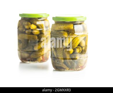 Small pickles. Marinated pickled cucumbers in jar isolated on white background. Stock Photo