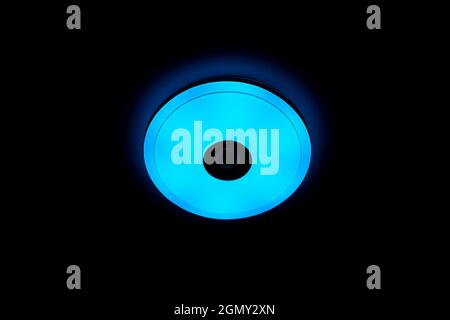Blue light LED ceiling light with built-in wireless speakers over black background. Stock Photo