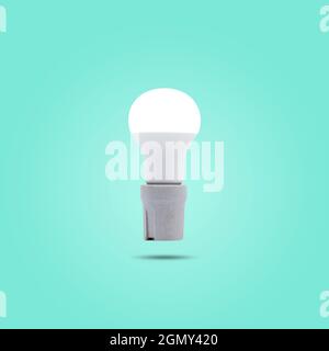 LED energy saving lamp 230v in a ceramic socket isolated on green pastel color background. Stock Photo