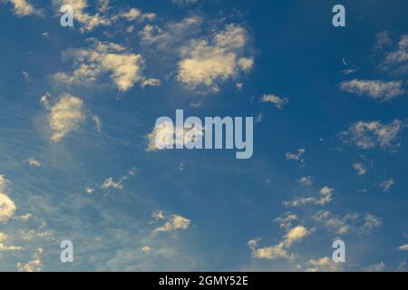 Small clouds scattered during sunset. Small moon at an angle. Resource for replacement of skies. Stock Photo
