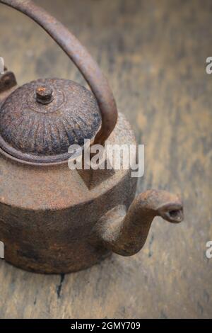 Old Rusty Iron Kettle on a Wooden table top Stock Photo