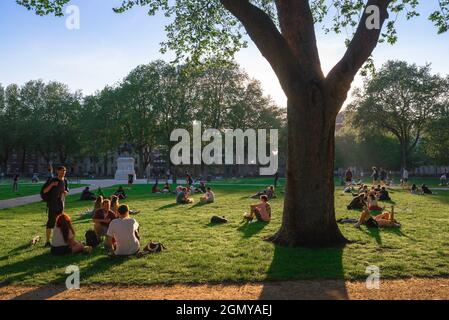 Park summer people, view of young people relaxing on a hot summer evening in Queen Square, a park in the centre of the city of Bristol, England, UK Stock Photo