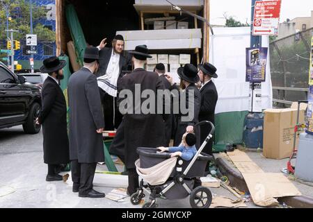 Orthodox Jewish men waiting to buy do it yourself Sukkahs from a man in a truck. On Lee Avenue in Williamsburg, Brooklyn, New York. Stock Photo