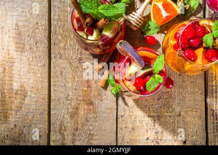 Traditional autumn winter drink hot spicy sangria - red, pink, white. With cider, pink red wine, apples, oranges, pomegranate, cranberry, plum, figs, Stock Photo