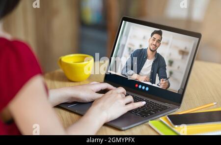 Smiling young arab guy student studying remotely, learning language with european woman teacher Stock Photo