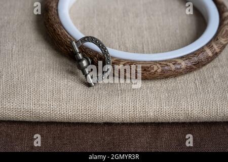 Set for embroidery. Brown linen fabric and hoop. Copy space, top view. Home crafts, embroidery Stock Photo