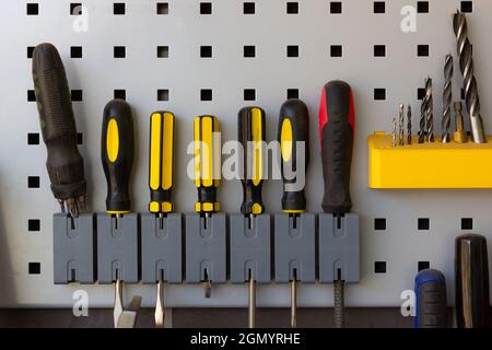 Screwdrivers, drill bits and tools nicely placed in repair shop wall. Industry work equipment concept Stock Photo