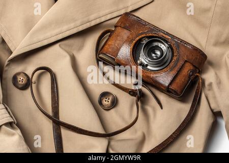 Old vintage camera with 50mm lens in brown leather case on beige trench coat Stock Photo