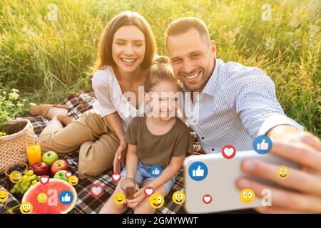 Happy young european family with little daughter on picnic taking selfie for social networks outdoor Stock Photo