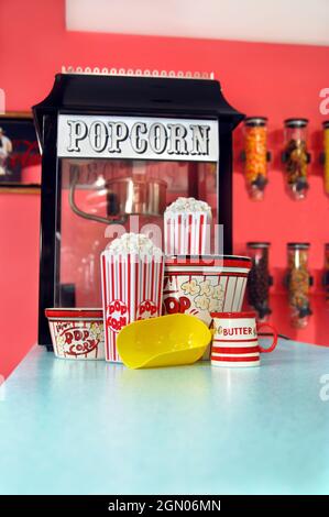 Home movies are so much better with fresh popcorn!  Popcorn sits in holders and yellow scoop sits ready for seconds. Stock Photo