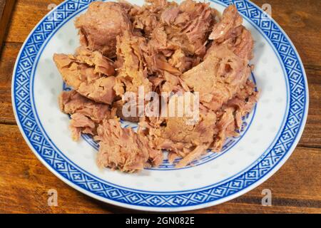 Canned tuna fish chunks in oil on a chinaware plate Stock Photo