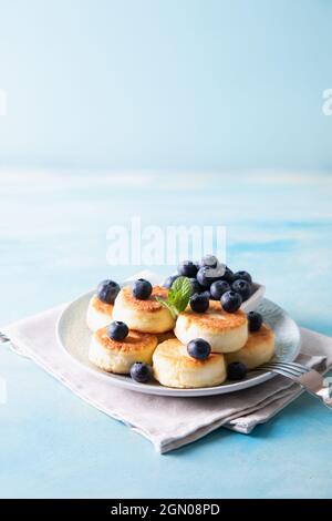 Cottage cheese pancakes. Cheesecakes from cottage cheese, delicious Breakfast, traditional Russian sweet pancakes. With blueberry, mint and honey. Stock Photo