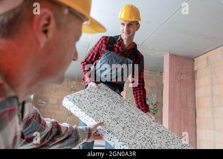 Happy male workers holding ceramic block at construction site Stock Photo