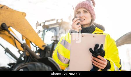 Woman with walkie talky on compost facility dispatching deliveries Stock Photo