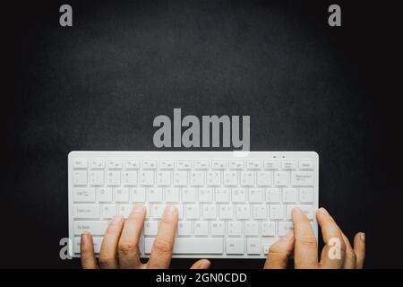hands typing on a white computer keyboard, Black background, Place for an inscription Stock Photo