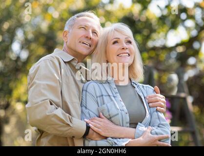 Loving senior couple enjoying warm days and peaceful nature, spouses spending time together outdoors, man embracing wife and smiling, copy space Stock Photo
